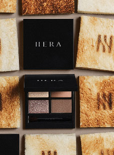 독특하게 배열된 토스트 조각들 위에 놓인 활짝 열린 헤라 아이섀도우 팔레트가 반짝이는 글리터와 부드러운 브라운 계열 색상으로 2025 홀리데이 컬렉션의 화려한 글램룩을 제안한다.