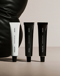 HERA 로고가 새겨진 화이트, 블랙 튜브형 핸드 케어 크림 3개가 일렬로 진열되어 HERA 2025 홀리데이 컬렉션의 품격 있는 글램함을 선사한다.