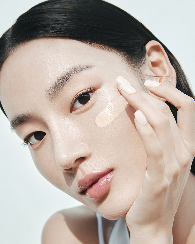 여성 모델이 손으로 헤라 제품을 얼굴에 섬세하게 바르는 모습으로, 자연스러운 광채 피부를 연출하는 모습이 'LET YOUR GLOW SPEAK' 캠페인의 메시지를 효과적으로 전달합니다.