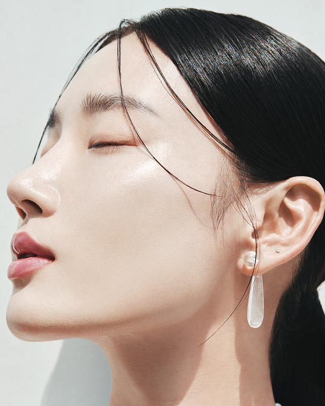 눈을 감은 여성의 옆모습이 햇살을 받아 빛나는 도자기처럼 매끄러운 피부와 함께, 헤라의 광채를 드러내는 LET YOUR GLOW SPEAK 캠페인의 이미지입니다.